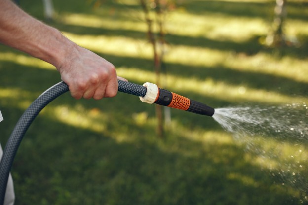 hombre-regando-sus-plantas-en-su-jardin-hombre-con-camisa-azul.jpg